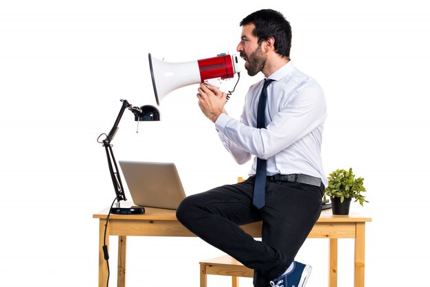 Empresário em seu escritório gritando por megafone