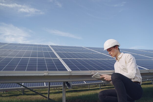 Empresário em um capacete branco perto da bateria solar