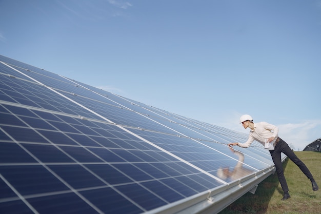 Empresário em um capacete branco perto da bateria solar