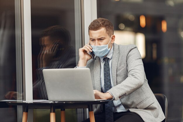 Empresário em uma cidade. pessoa com máscara. cara com laptop.