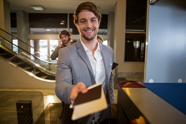 Foto grátis empresário, entregando seu cartão de embarque no balcão