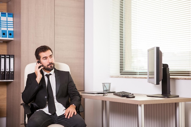 Empresário falando ao telefone e trabalhando no escritório. Empresário em ambiente profissional