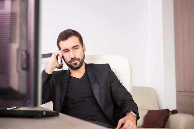 Empresário falando ao telefone enquanto trabalhava em seu escritório. Empresário em ambiente profissional