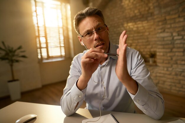 Empresário gesticulando explicando algo enquanto trabalhava no escritório e olhando para a câmera