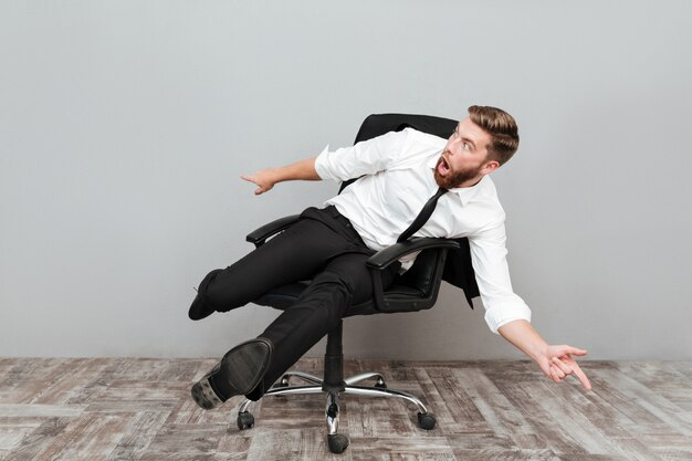 Empresário louco engraçado se divertindo enquanto está sentado na cadeira do escritório
