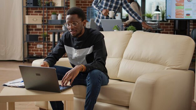 Empresário masculino acenando para a webcam de reunião de videochamada no laptop, usando telecomunicações remotas em videoconferência online. Gerente de projeto conversando com pessoas em teleconferência.