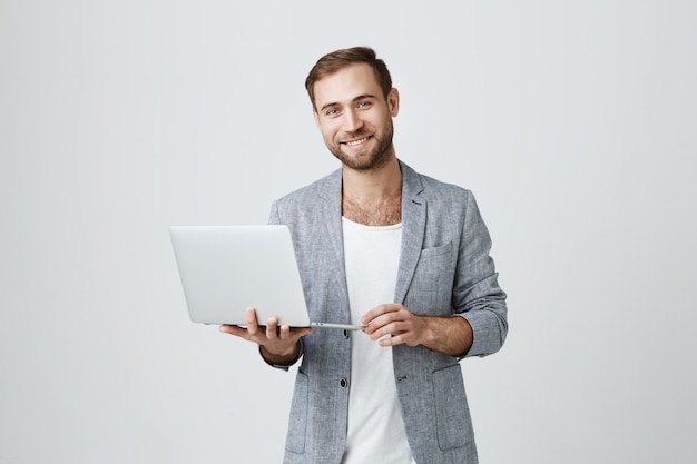 Empresário masculino bonito usando laptop