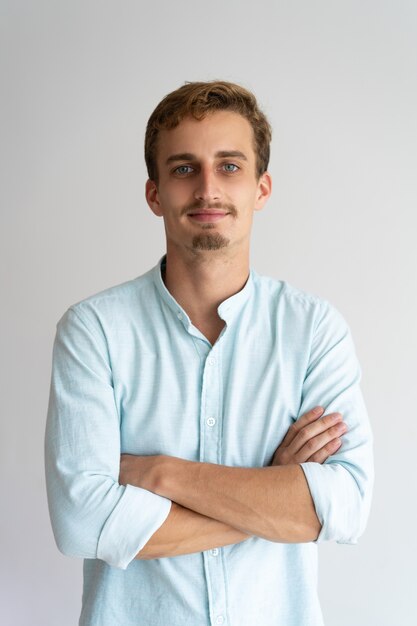 Empresário masculino sorridente com barba e bigode, cruzando os braços no peito