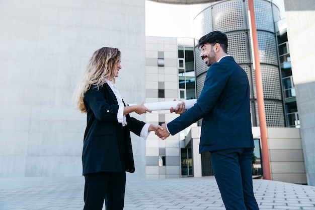 Empresário moderno e empresária apertando as mãos