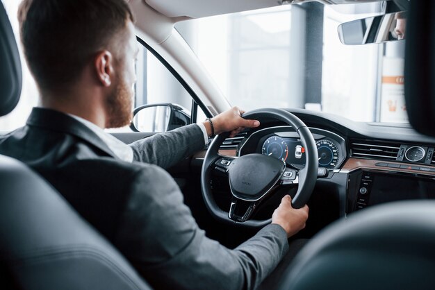 Empresário moderno experimentando seu novo carro no salão automotivo