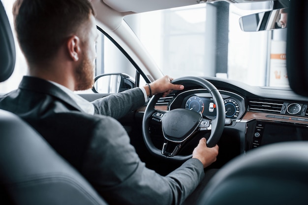 Empresário moderno experimentando seu novo carro no salão automotivo