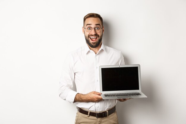 Empresário mostrando a tela do laptop, parecendo animado, em pé