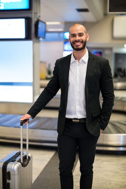 Empresário parado com bagagem na área de espera do aeroporto