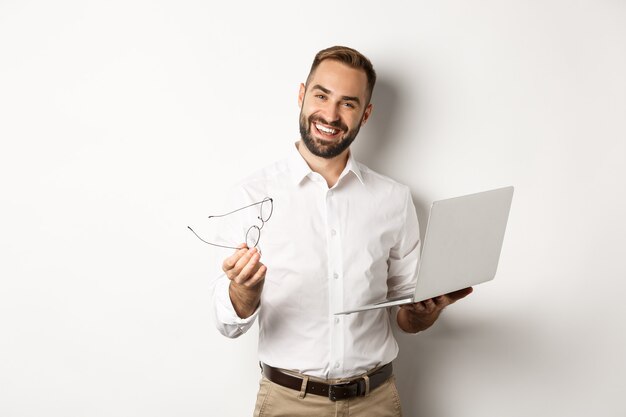 Empresário satisfeito elogiando o bom trabalho enquanto verifica o laptop, em pé