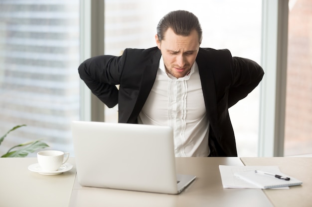 Foto grátis empresário sofre de dor nas costas no local de trabalho