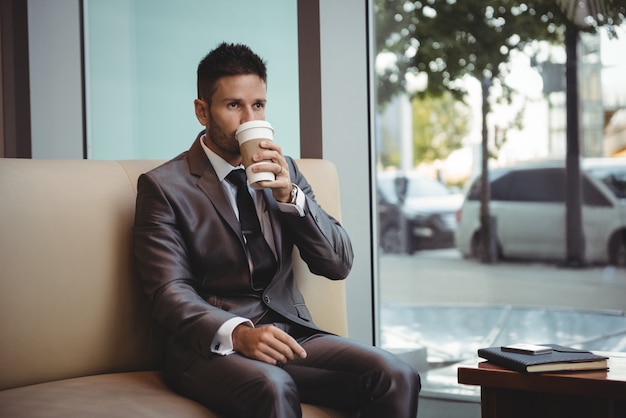 Empresário tomando café enquanto está sentado no sofá