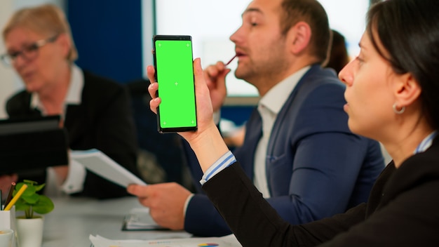 Empresários analisando relatórios financeiros anuais, sentados na mesa enquanto o funcionário segurando o telefone com monitor de tela verde. líder explicando a estratégia do projeto usando um pc com tela verde e display chroma key