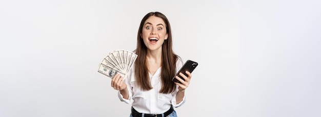 Foto grátis empréstimos de microcrédito online e conceito bancário mulher feliz segurando telefone celular e dinheiro sorrindo e