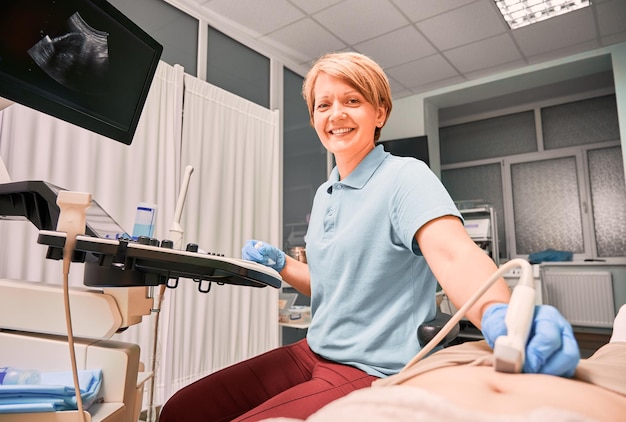 Encantadora médica fazendo exame de ultrassom na clínica