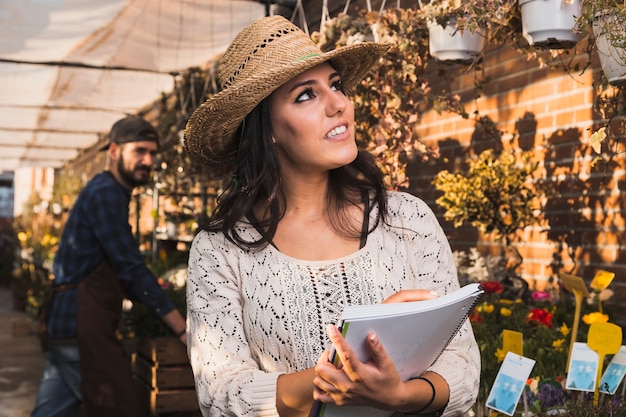 Encantadora mulher contando plantas em estufa