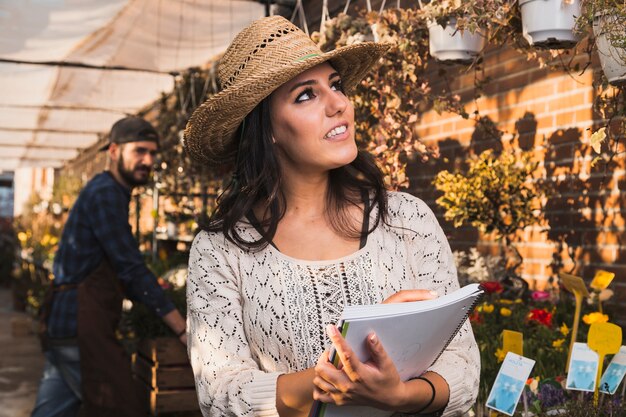 Encantadora mulher contando plantas em estufa