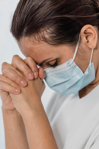 Enfermeira com máscara médica rezando