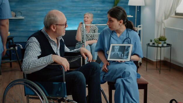 Enfermeira com raio-x em tablet mostrando digitalização para paciente idoso