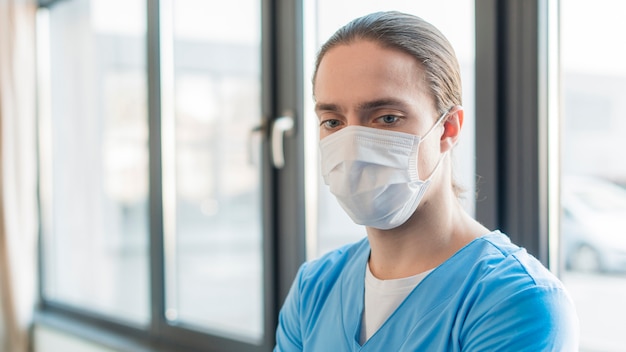 Enfermeira de alto ângulo masculino com máscara médica