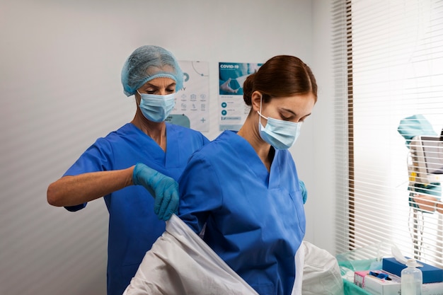 Foto grátis enfermeira de tiro médio ajudando médico