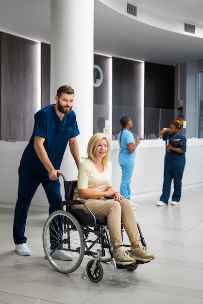 Enfermeira de vista lateral, ajudando o paciente em cadeira de rodas