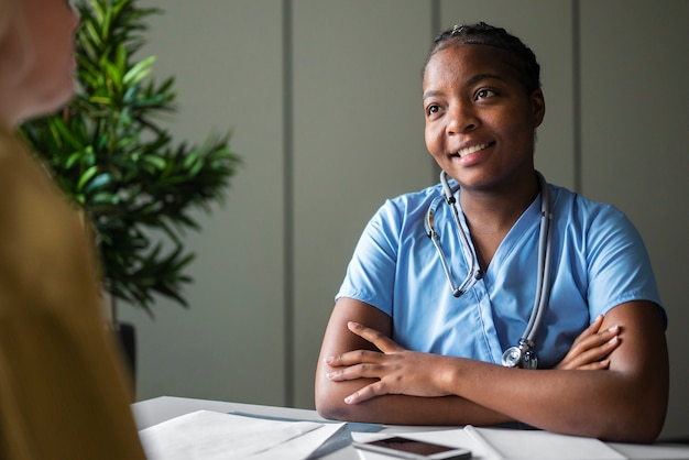 Enfermeira negra sorridente de tiro médio na mesa