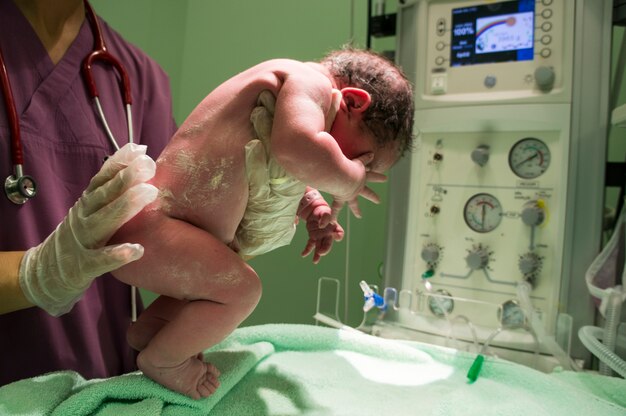 Enfermeira que prende o bebê recém-nascido