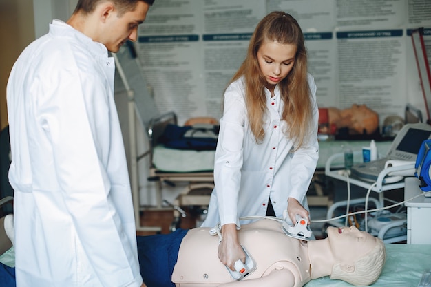 Enfermeira realiza reanimação. O médico ajuda a mulher a realizar a operação. Os alunos praticam medicina.