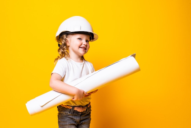 Engenheira de menina bonitinha com capacete segurando bluepring isolado na parede amarela