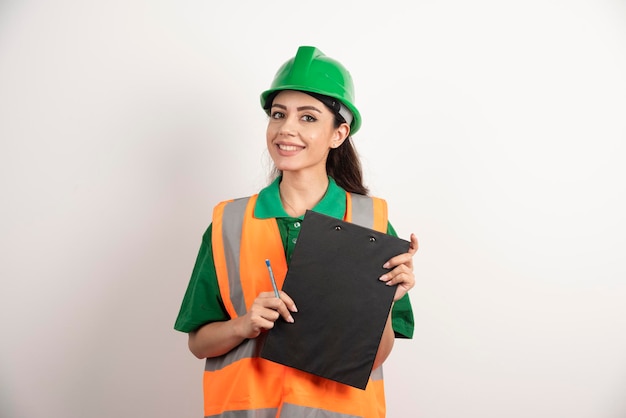 Engenheira sorridente segurando a prancheta no fundo branco. Foto de alta qualidade