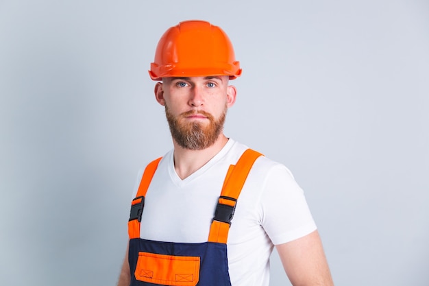 Engenheiro bonito na construção de capacete protetor em rosto sério focado em parede cinza