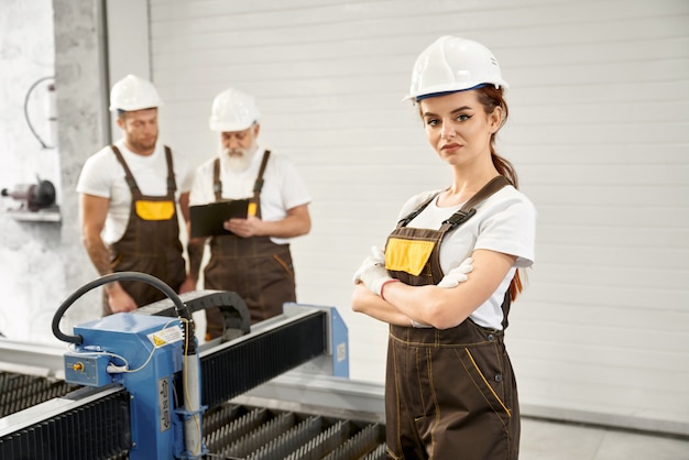 Engenheiro de mulher posando com trabalhadores na fábrica de metais.