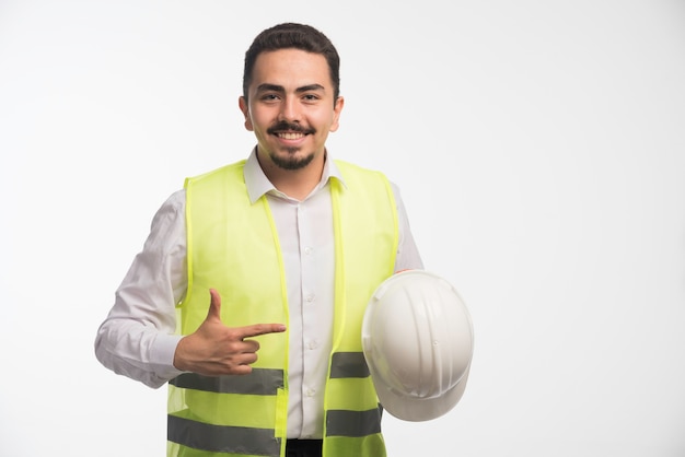 Engenheiro de uniforme segurando um capacete branco.