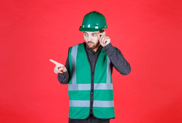 Engenheiro de uniforme verde e capacete mostrando o lado esquerdo.