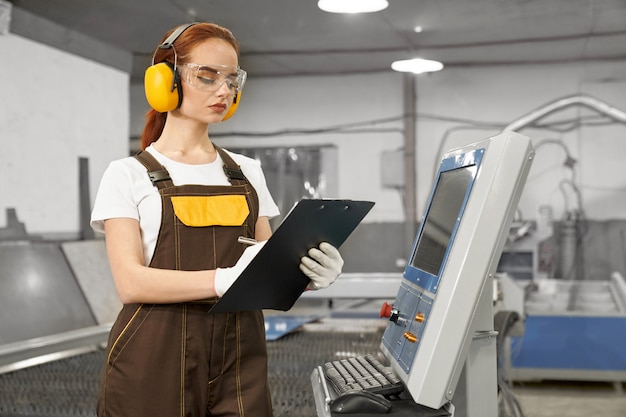 Engenheiro, segurando a pasta, operando a máquina computadorizada.