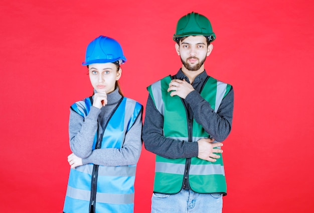 Engenheiros masculinos e femininos usando capacete e equipamento parecem confusos e pensativos.