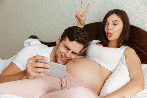 Engraçado casal jovem grávida tomando selfie
