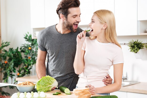 Engraçado jovem casal apaixonado em pé na cozinha e cozinhar