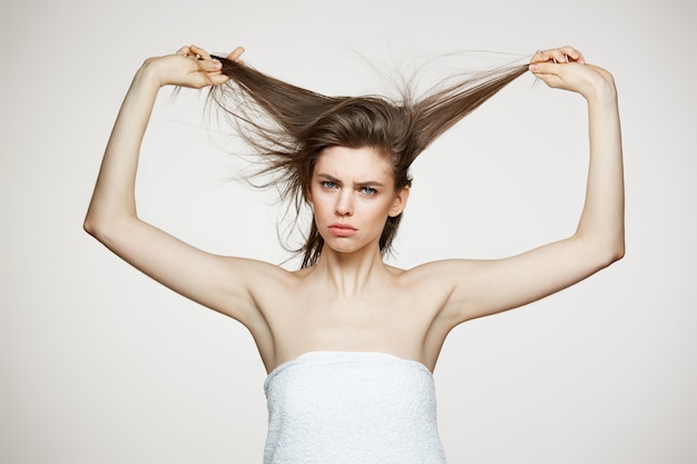 Engraçado jovem descontente em toalha tocar no cabelo. conceito de spa e cosmetologia de beleza.