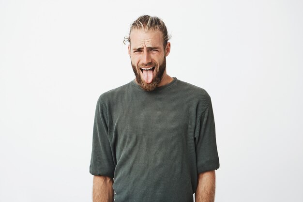 Engraçado jovem sueco com penteado na moda e barba saindo da língua