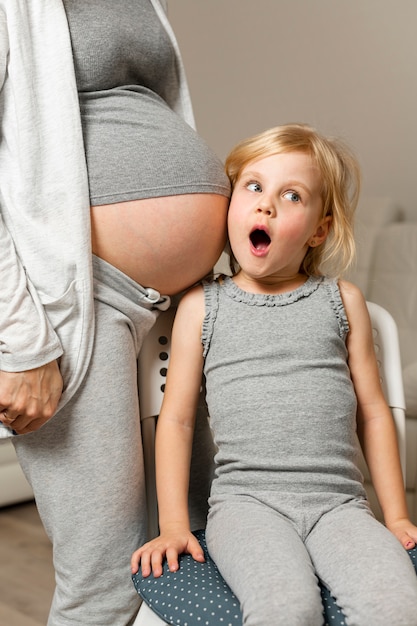 Engraçado menina escuta mãe barriga grávida