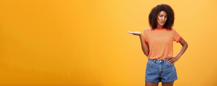 Foto grátis então, que namorada de pele escura elegante e mal-humorada com penteado encaracolado, segurando a mão na cintura
