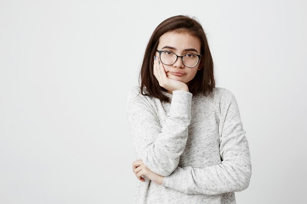 entediada mulher adolescente bonita irritada com cabelos escuros lisos olhando