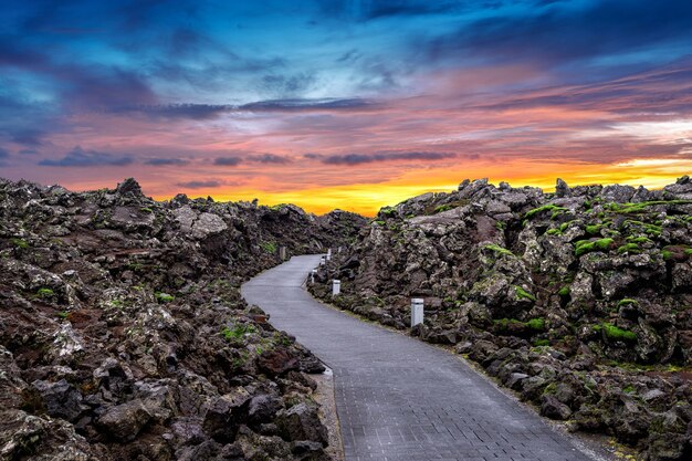 Entrada da lagoa azul com rochas de lava e musgo verde ao pôr do sol na Islândia.