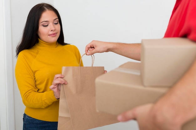 Entregador dando uma sacola de compras para uma mulher